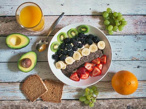 fruit on a plate and whole grain bread, avocado, orange juice