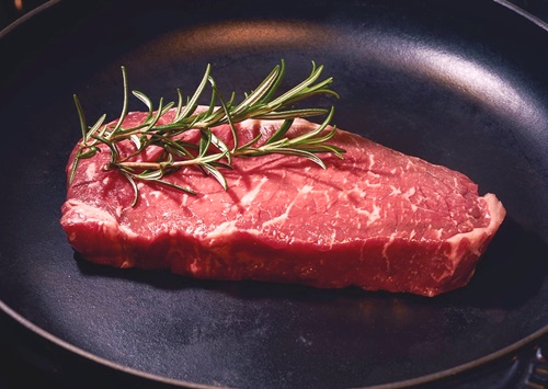 raw steak in a pan garnished with rosemary