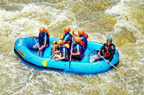 people wearing helmets in a raft in rough waters